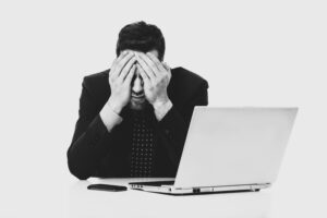 Uomo d'affari disperato davanti al computer, che rappresenta l'impatto economico di un errore nella selezione del personale o nel retention rate aziendale.